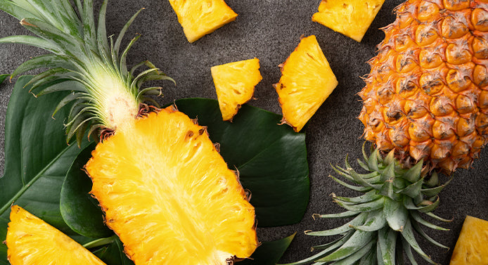 Pineapples on a grey background, whole, sliced, and chunks, bromelain is found in pineapple