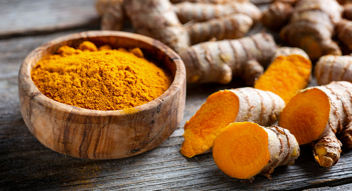 Turmeric root and powdered Curcumin on a wooden table