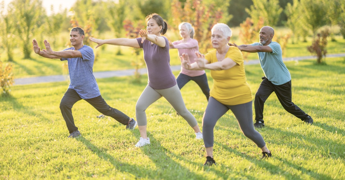 Natural Chronic Pain Relief Strategies - A small group of mature adults practice Tai Chi outdoors together on a warm summer day.